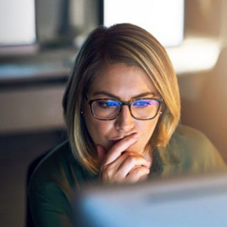 Vrouw met een bril op kijkt naar haar laptop