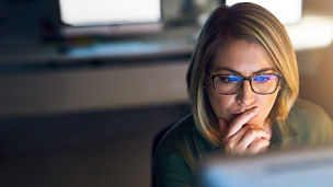woman wearing specs looking at computer screen