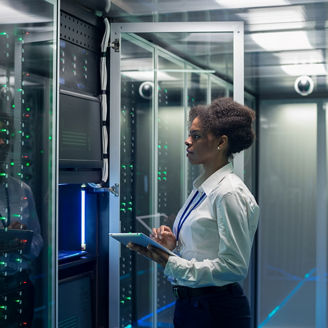People looking at a laptop whilst leaning on a desk in an office