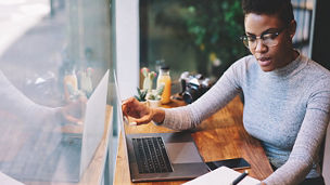 Woman with laptop writing in notepad