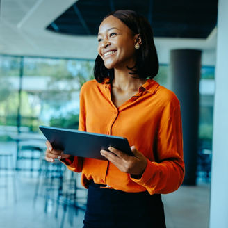A woman with a tablet standing in an open-plan office.