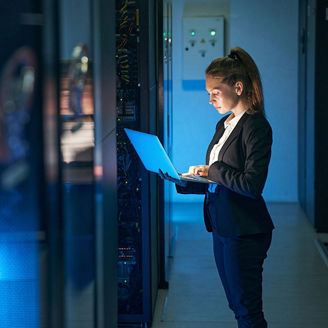 Woman working on laptop near servers