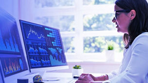 Woman working on multiple computer screens