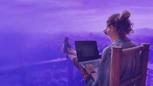 vrouw met laptop op haar schoot en benen over tafel aan het werk