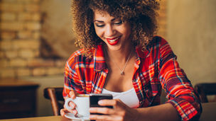 Young woman at cafe drinking coffee and using mobile phone