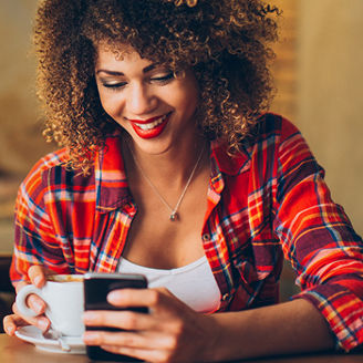 Young woman at cafe drinking coffee and using mobile phone