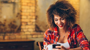 Young woman at cafe drinking coffee and using mobile phone