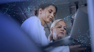 Women healthcare professionals wearing white labcoats holding laptop