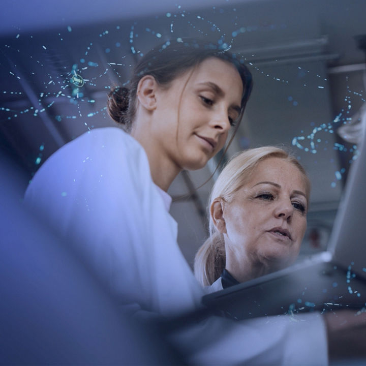 Women healthcare professionals wearing white labcoats holding laptop