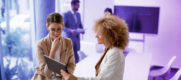 Two collegues looking at tablet in meeting room
