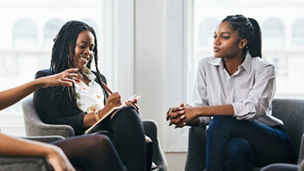 A person putting coins in a jar whilst using a pen and paper