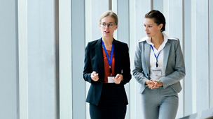 Two businesswomen walking together in a hallway