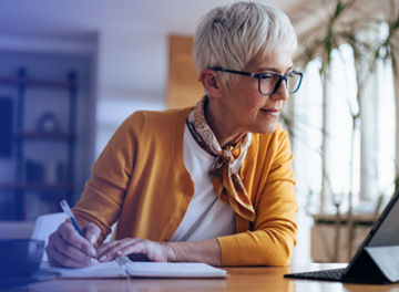 woman writing and looking at the ipad