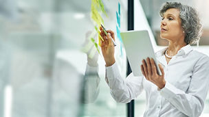 Women writing and making notes on a transparent glass board