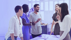 Smiling colleagues working together at desk in office discussing papers