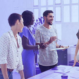 Smiling colleagues working together at desk in office discussing papers