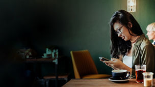 Young woman sitting in cafe using smartphone
