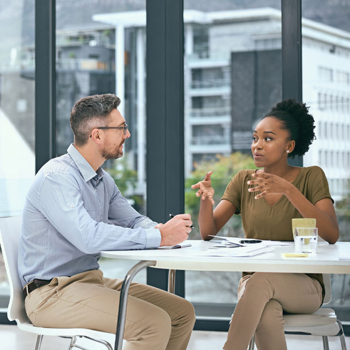 Two colleagues are chatting at a table